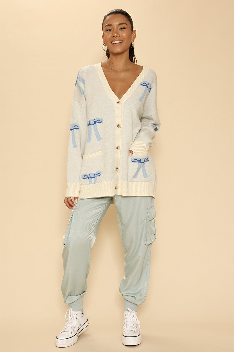 All Over Bow Knit Cardigan. Oversized V-Neck, Button Front & Pockets
